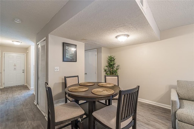 dining area with hardwood / wood-style floors and a textured ceiling