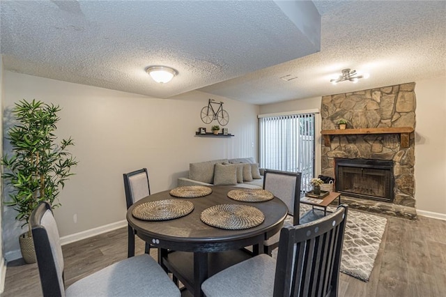 dining space with a textured ceiling, a fireplace, and hardwood / wood-style flooring