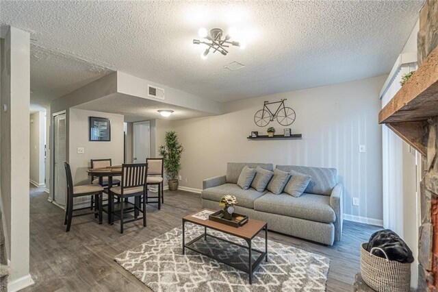 living room featuring hardwood / wood-style floors, a notable chandelier, and a textured ceiling