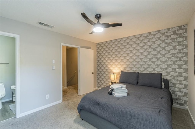 carpeted bedroom with ensuite bath and ceiling fan