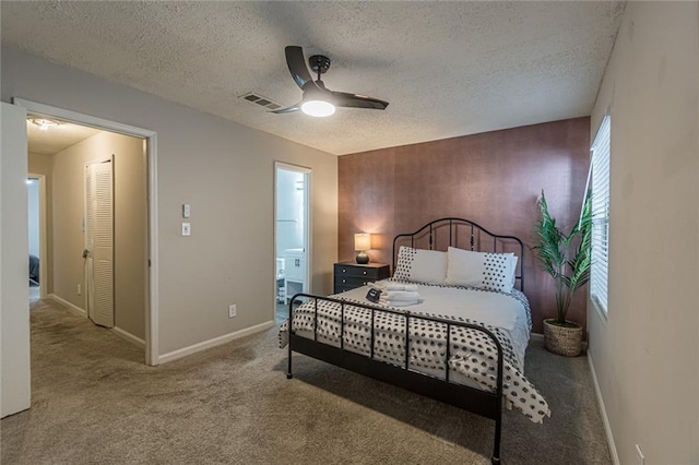 carpeted bedroom featuring ensuite bathroom, a textured ceiling, and ceiling fan