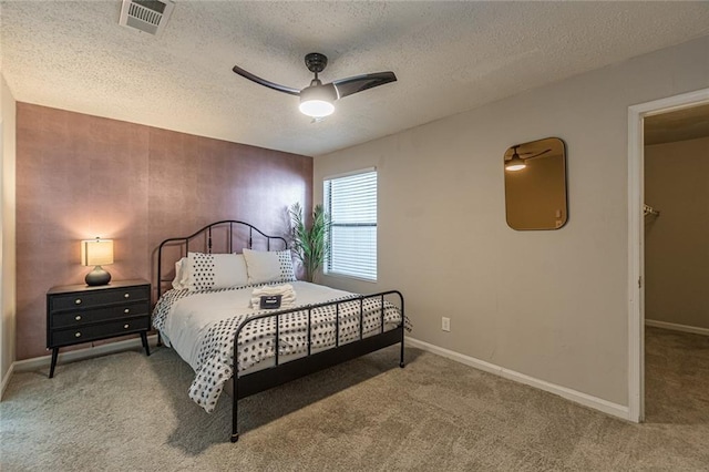 carpeted bedroom with ceiling fan and a textured ceiling