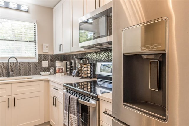 kitchen featuring white cabinets, backsplash, range, refrigerator, and sink