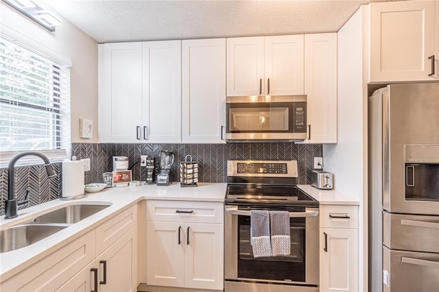 kitchen with white cabinetry, tasteful backsplash, appliances with stainless steel finishes, and sink