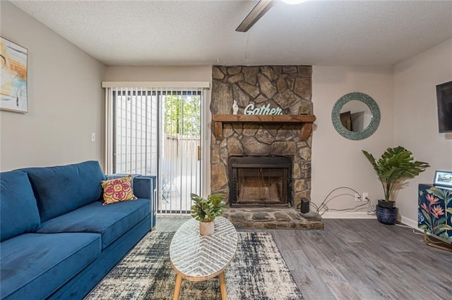 living room featuring a textured ceiling, wood-type flooring, and a fireplace