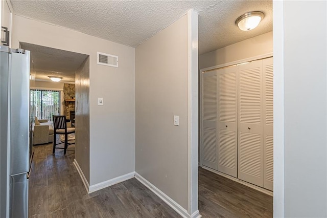 hall with dark wood-type flooring and a textured ceiling