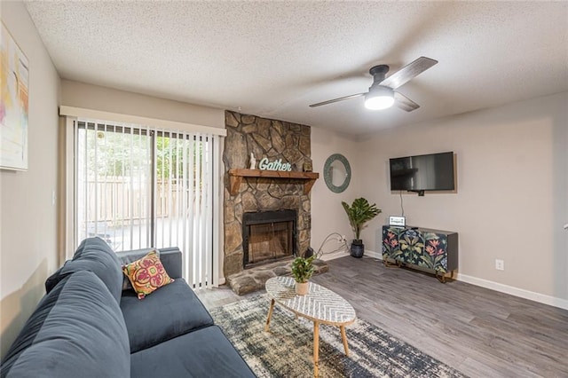 living room with a textured ceiling, wood-type flooring, a fireplace, and ceiling fan