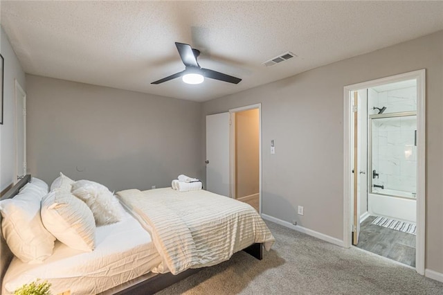 bedroom with light carpet, a textured ceiling, ensuite bathroom, and ceiling fan