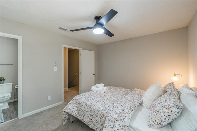 carpeted bedroom with ensuite bath and ceiling fan