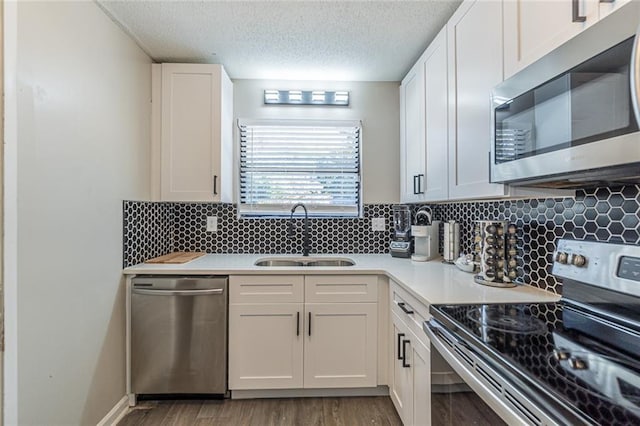 kitchen with appliances with stainless steel finishes, sink, decorative backsplash, and white cabinets