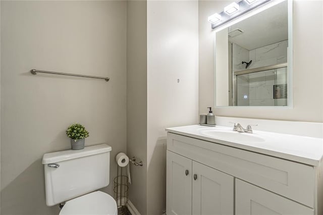 bathroom with a shower with door, vanity, and toilet