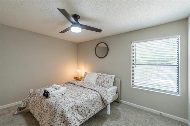 bedroom with ceiling fan, light carpet, and a textured ceiling