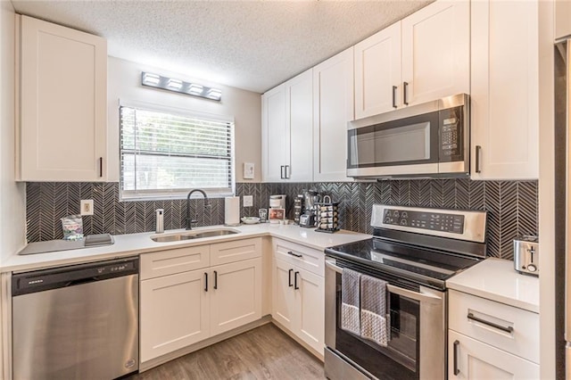 kitchen featuring a textured ceiling, white cabinets, stainless steel appliances, and sink