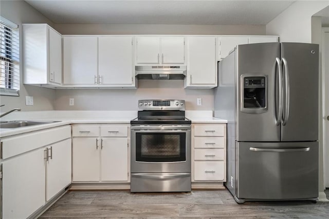 kitchen featuring stainless steel appliances, sink, light wood-type flooring, and white cabinets