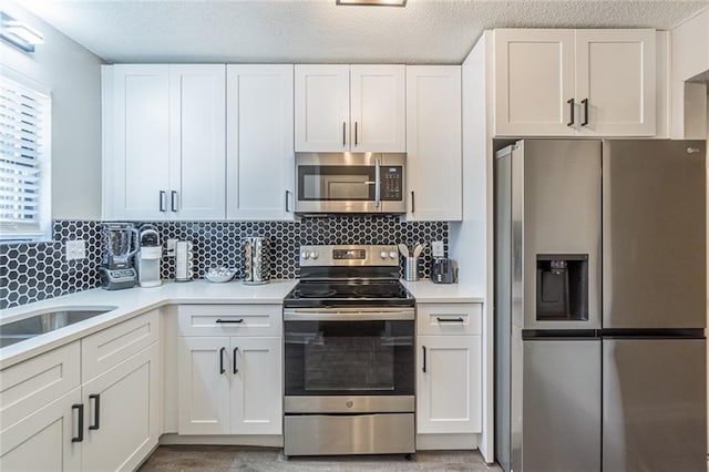 kitchen featuring appliances with stainless steel finishes, a textured ceiling, and white cabinets