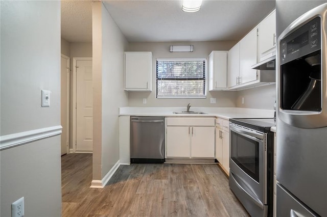 kitchen with sink, white cabinetry, light hardwood / wood-style floors, stainless steel appliances, and extractor fan