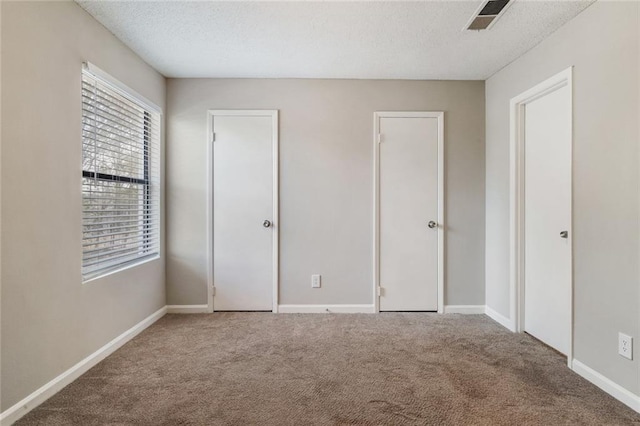 unfurnished bedroom with a textured ceiling and carpet floors