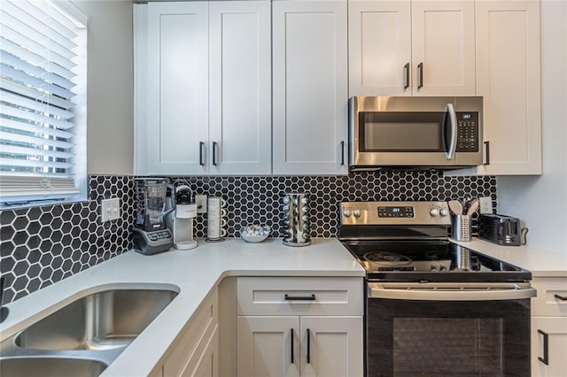 kitchen with white cabinets, tasteful backsplash, and stainless steel appliances