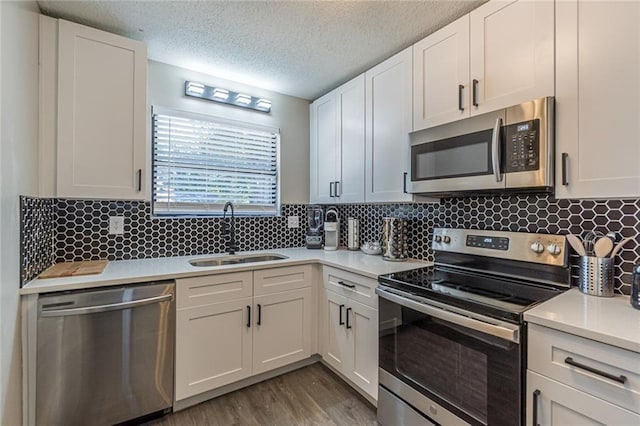 kitchen featuring backsplash, sink, appliances with stainless steel finishes, and white cabinetry