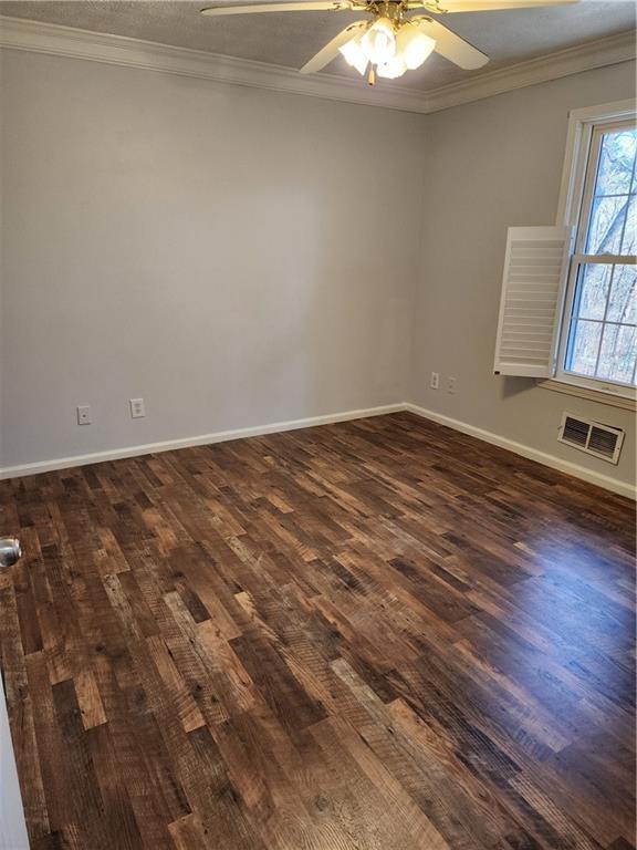 unfurnished room with crown molding, ceiling fan, and dark wood-type flooring