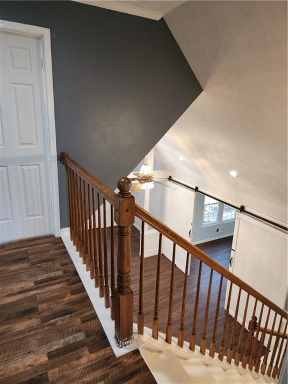 staircase featuring hardwood / wood-style flooring, a barn door, and vaulted ceiling