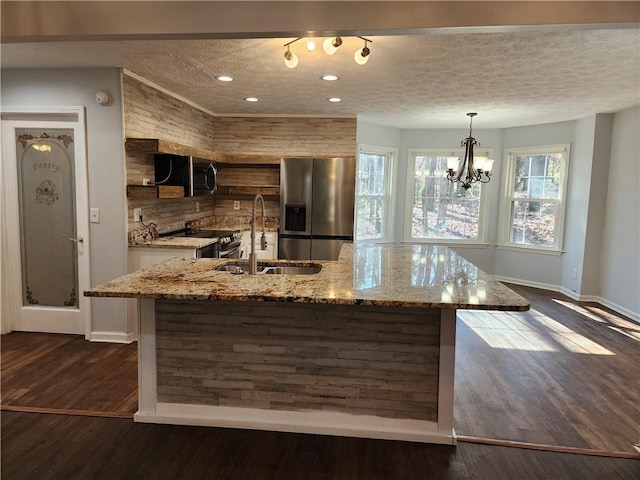 kitchen featuring a kitchen island, decorative light fixtures, sink, light stone counters, and stainless steel appliances