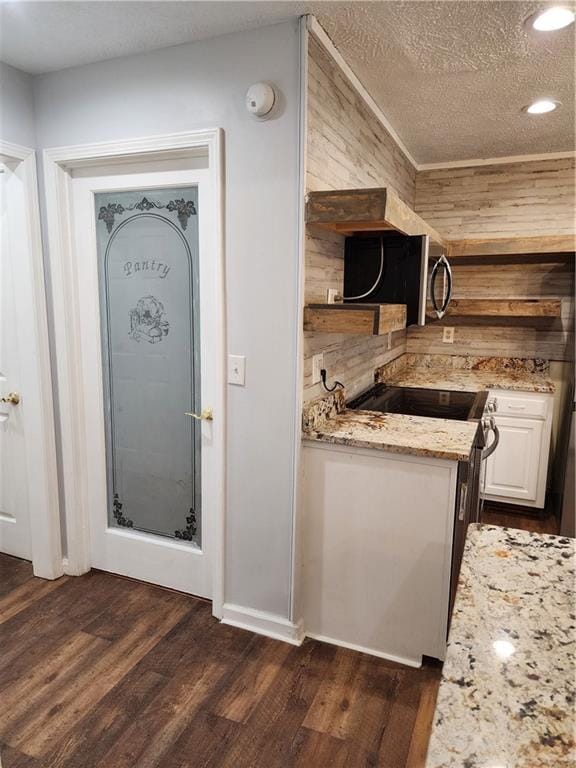 kitchen with white cabinetry, dark hardwood / wood-style flooring, electric range, light stone countertops, and a textured ceiling