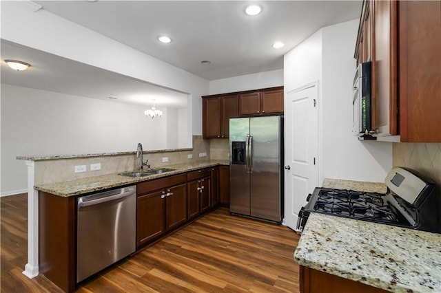 kitchen featuring a sink, stainless steel appliances, a peninsula, dark wood finished floors, and decorative backsplash
