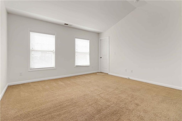 spare room with light colored carpet, baseboards, and vaulted ceiling