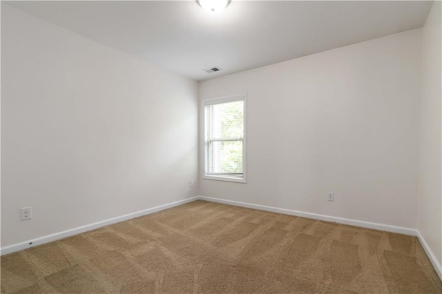 empty room featuring light carpet and baseboards