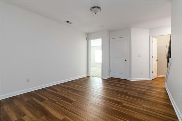 empty room featuring dark wood-type flooring and baseboards