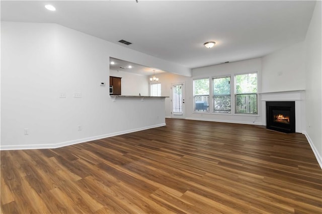 unfurnished living room with dark wood-type flooring, a fireplace with flush hearth, recessed lighting, baseboards, and a chandelier