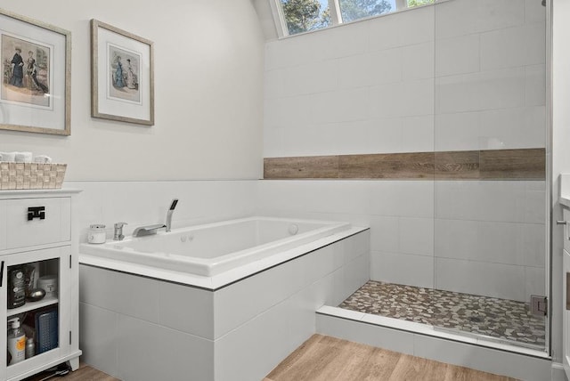 full bathroom with a stall shower, wood finished floors, a garden tub, and a skylight