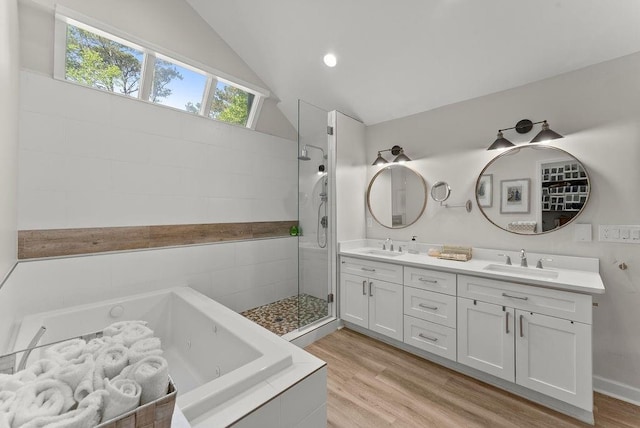 full bathroom with a tub with jets, tiled shower, double vanity, wood finished floors, and lofted ceiling