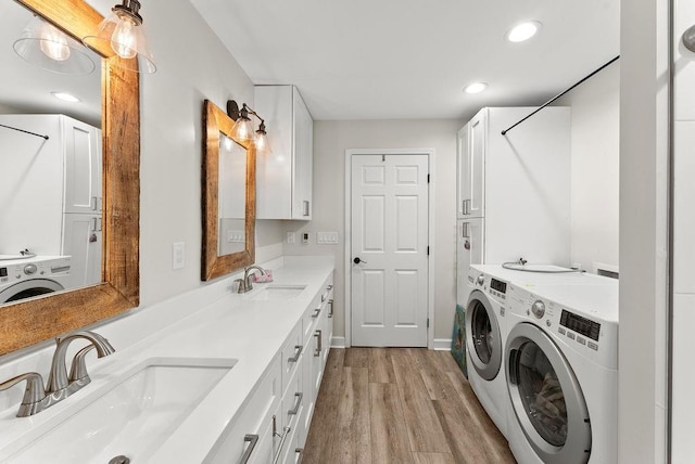 washroom with separate washer and dryer, light wood-style floors, recessed lighting, and cabinet space