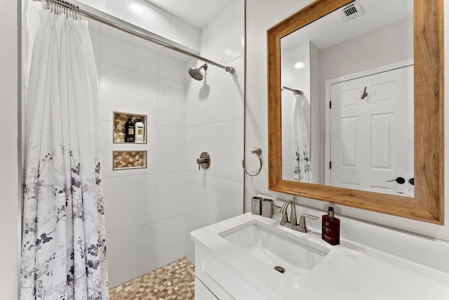 bathroom featuring a tile shower and vanity