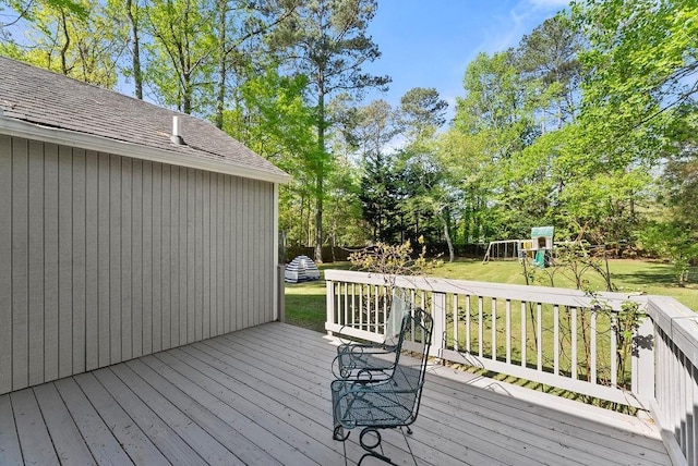 wooden terrace with a playground, a yard, and view of wooded area