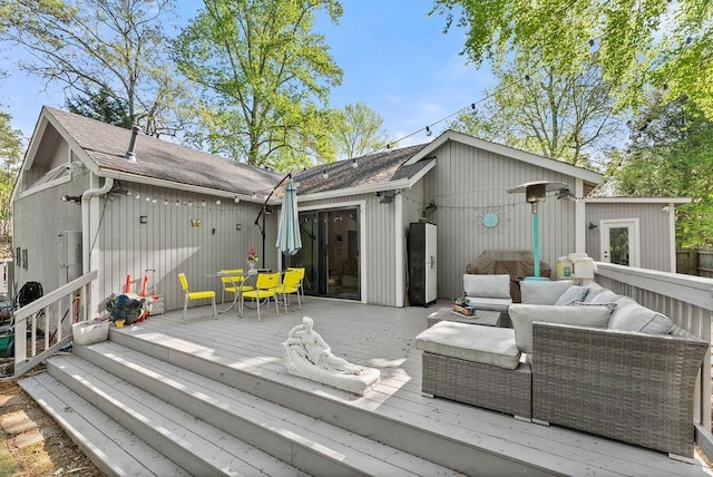 rear view of house featuring outdoor lounge area, a wooden deck, and roof with shingles
