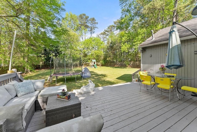 wooden terrace featuring a trampoline, an outdoor hangout area, a playground, and view of wooded area