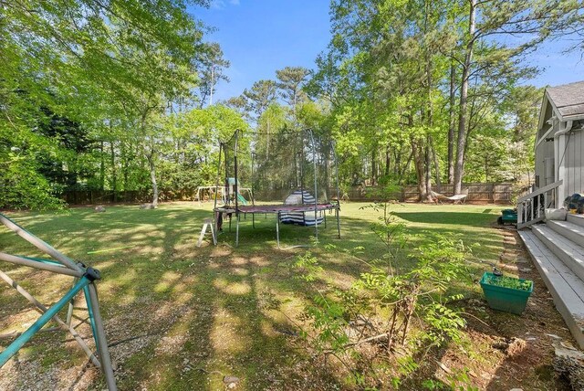view of yard featuring a trampoline and view of wooded area