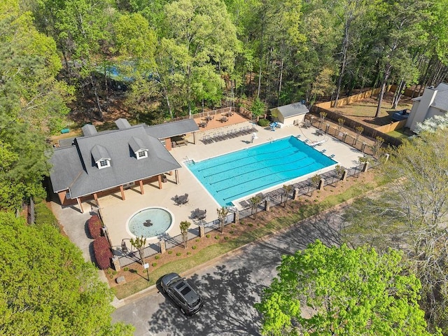 bird's eye view of a pool and a heavily wooded area