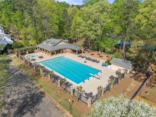 community pool with fence, a patio, and a forest view