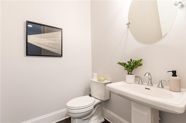 bathroom with toilet, baseboards, and a sink