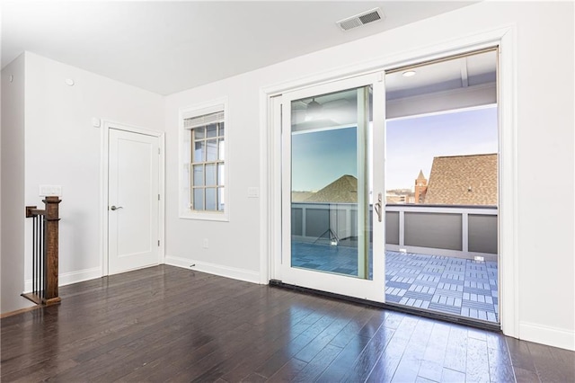 unfurnished room featuring visible vents, baseboards, and wood finished floors