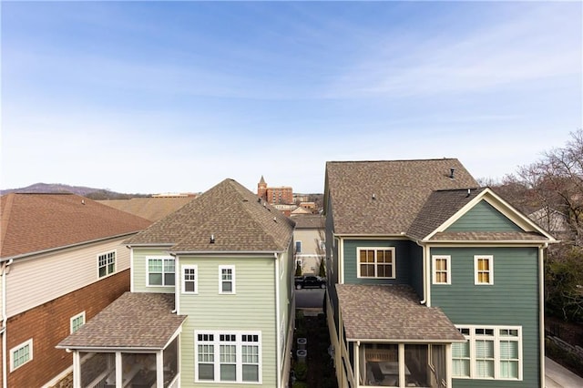 rear view of property with a sunroom and a shingled roof