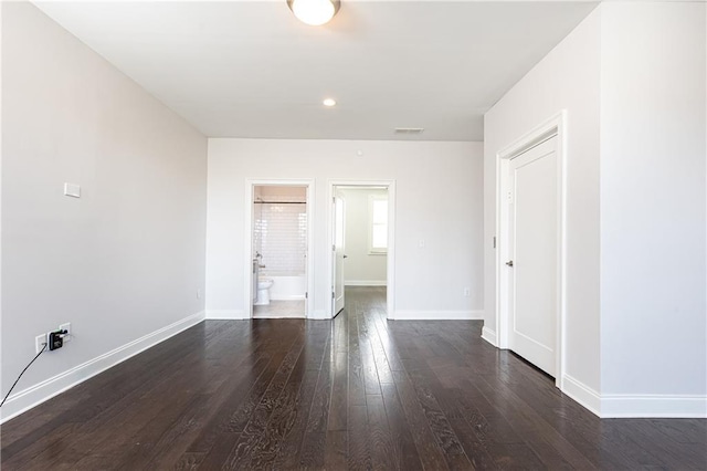 unfurnished room featuring visible vents, baseboards, and dark wood-style floors