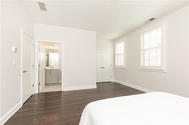 bedroom with wood finished floors, visible vents, and baseboards