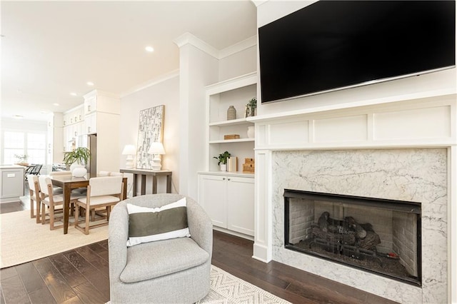 sitting room with recessed lighting, dark wood-type flooring, ornamental molding, and a high end fireplace