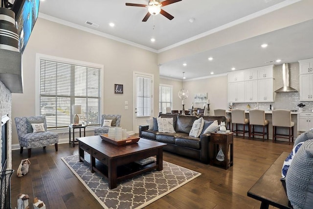 living room with dark hardwood / wood-style flooring, a fireplace, ornamental molding, and ceiling fan