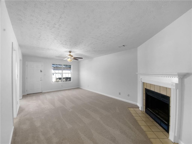 unfurnished living room with light carpet, a ceiling fan, visible vents, baseboards, and a tiled fireplace